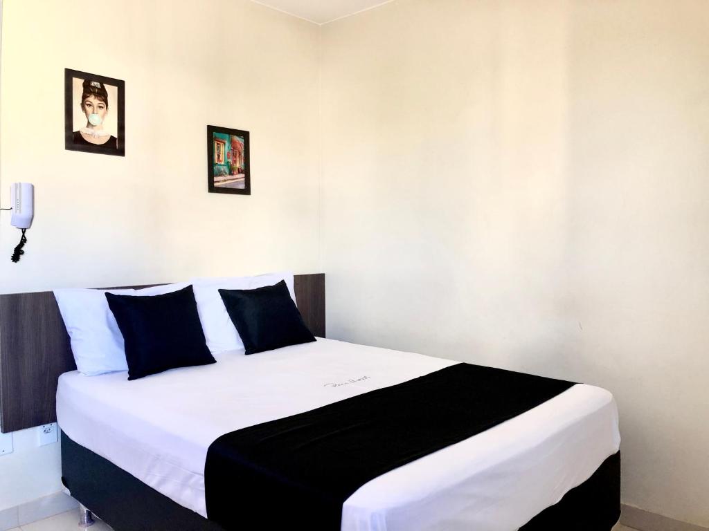 a bedroom with a large bed with black and white sheets at Paris Hotel by H Hotéis - Business in Taguatinga