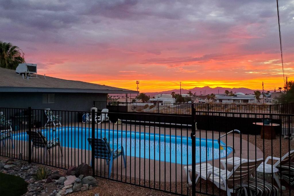 a pool with chairs and a sunset in the background at Lake Havasu Apartment with Pool 4 Mi to Beach! in Lake Havasu City