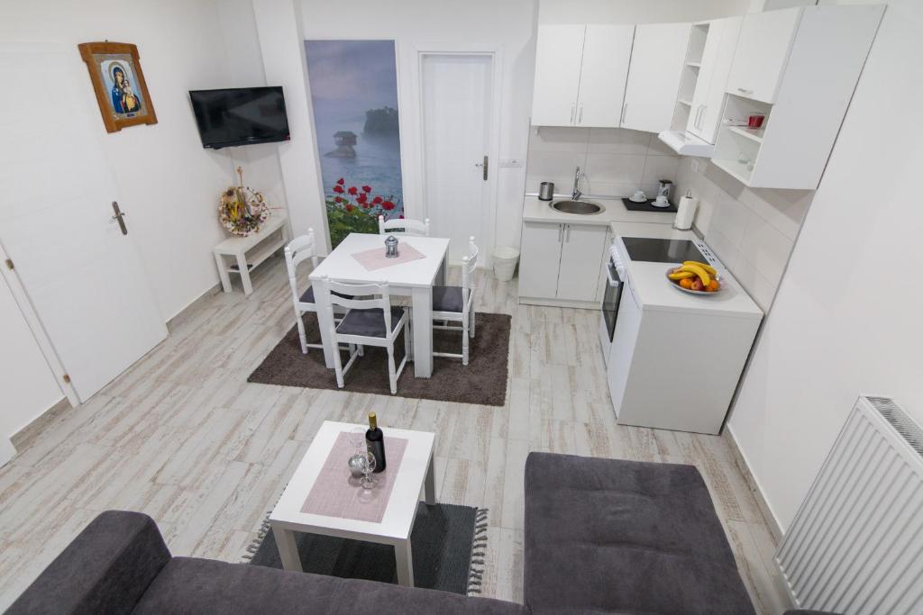 eine kleine Küche mit weißen Schränken und einem Tisch in der Unterkunft Apartment BB in Bajina Bašta