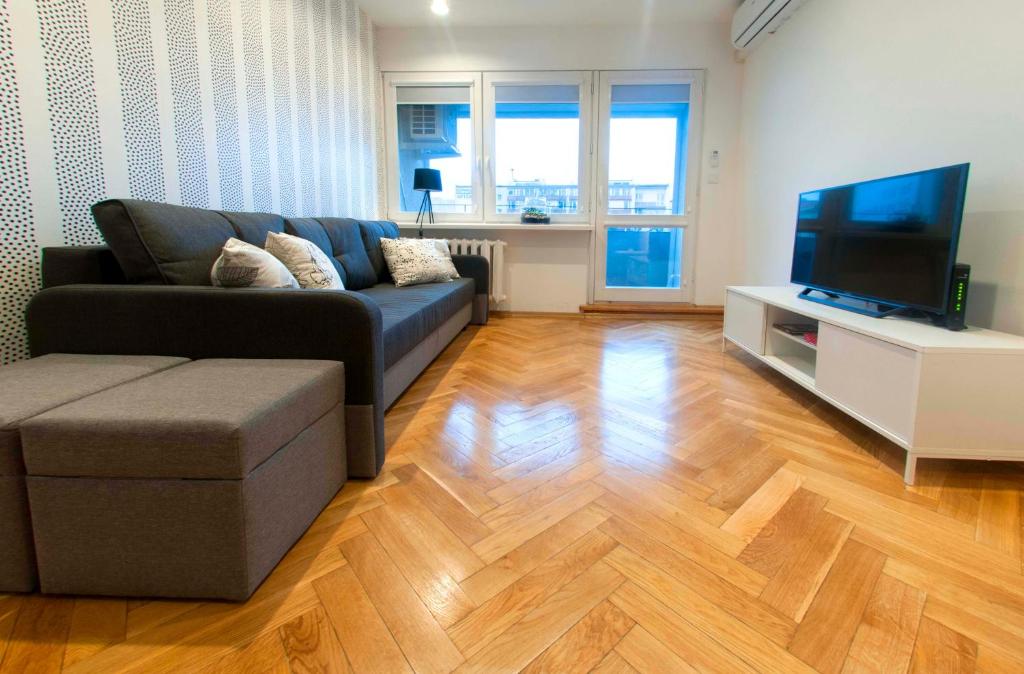 ein Wohnzimmer mit einem Sofa und einem Flachbild-TV in der Unterkunft Bielańska Apartment in Warschau