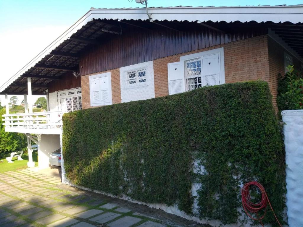 dom z zielonym żywopłotem przed nim w obiekcie Casa Papai Noel w mieście Campos do Jordão