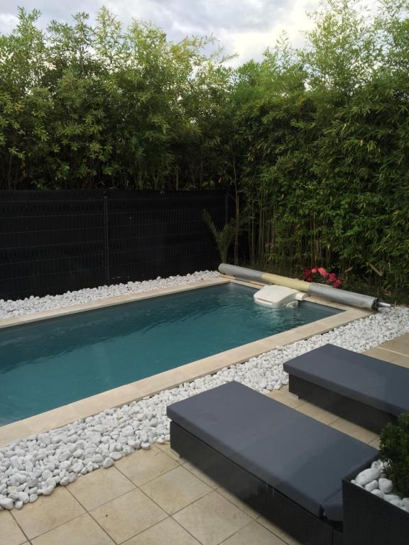 a swimming pool in a backyard with rocks and trees at La Villa W’ILLYS in Montpellier