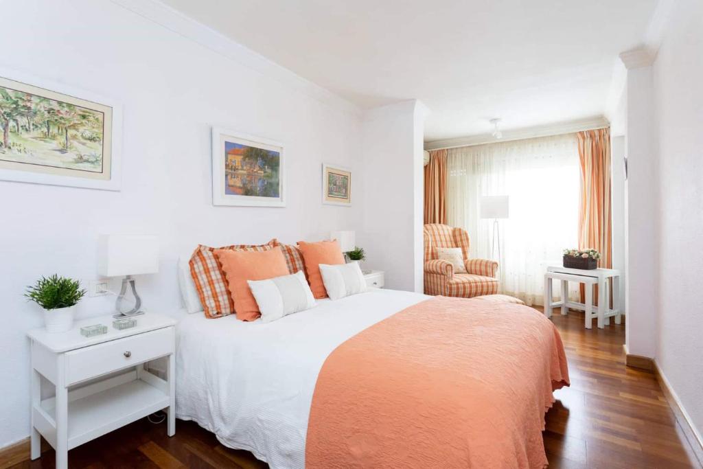 a white bedroom with a large bed with orange pillows at Sweet Home in Santa Cruz de Tenerife