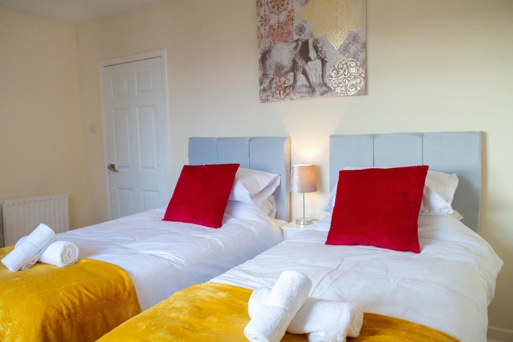 2 camas en una habitación con almohadas rojas y blancas en Carvetii - Derwent House - Spacious 2nd floor flat, en Grangemouth