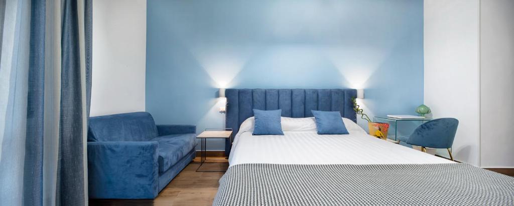 a bedroom with a bed and a blue couch at B&B Campari 10 in Pavia