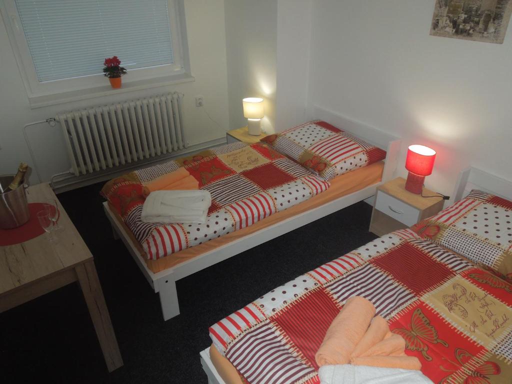 a room with two beds and a table with two lamps at Penzion Cristal in Rossitz