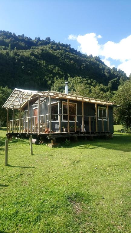 ein Haus, das auf einem Feld sitzt in der Unterkunft Cabaña Río Cochamó in Cochamó