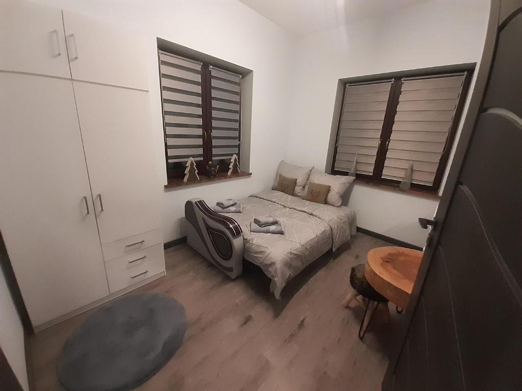 a bedroom with a bed and a table and two windows at Dziupla u Górala in Szaflary