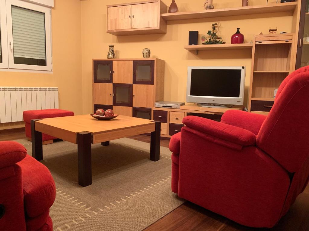 Sala de estar con 2 sillas rojas y TV en Oktheway San Eufrasio en Sarria