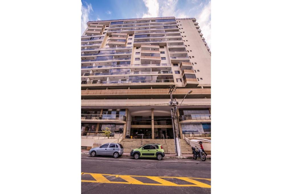 un edificio alto con coches estacionados frente a él en Praia Dourada en Vila Velha