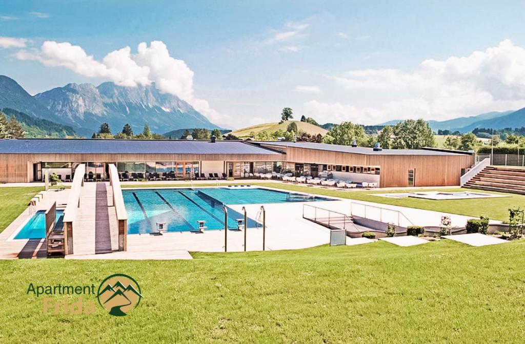 a large swimming pool in front of a building with mountains at Apartment Frida by Da Alois in Gröbming
