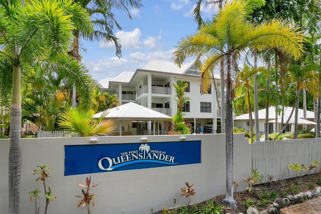 una casa blanca con palmeras y un cartel en Seascape Holidays at The Queenslander en Port Douglas