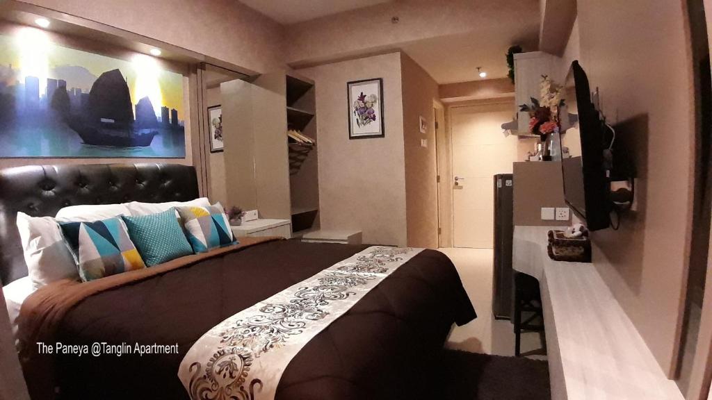 a bedroom with a large bed and a refrigerator at The Paneya @Tanglin Apartment in Surabaya