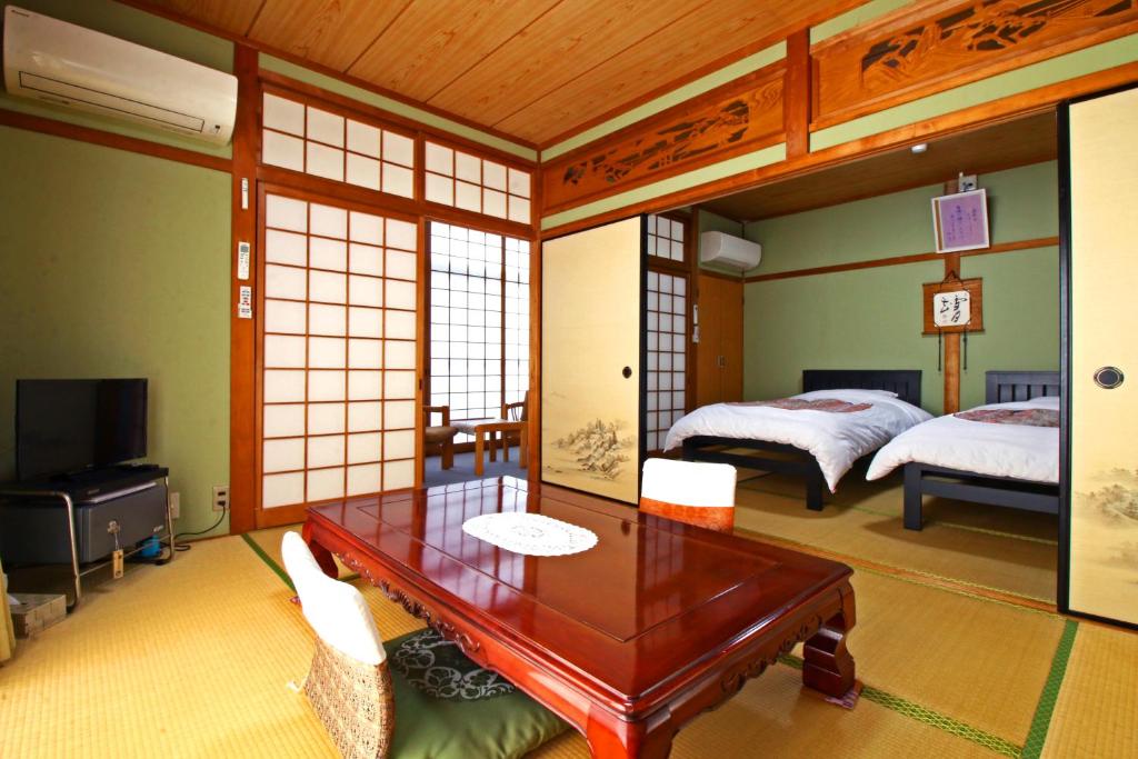 una habitación con 2 camas y una mesa en una habitación en Shirasakiso, en Yura