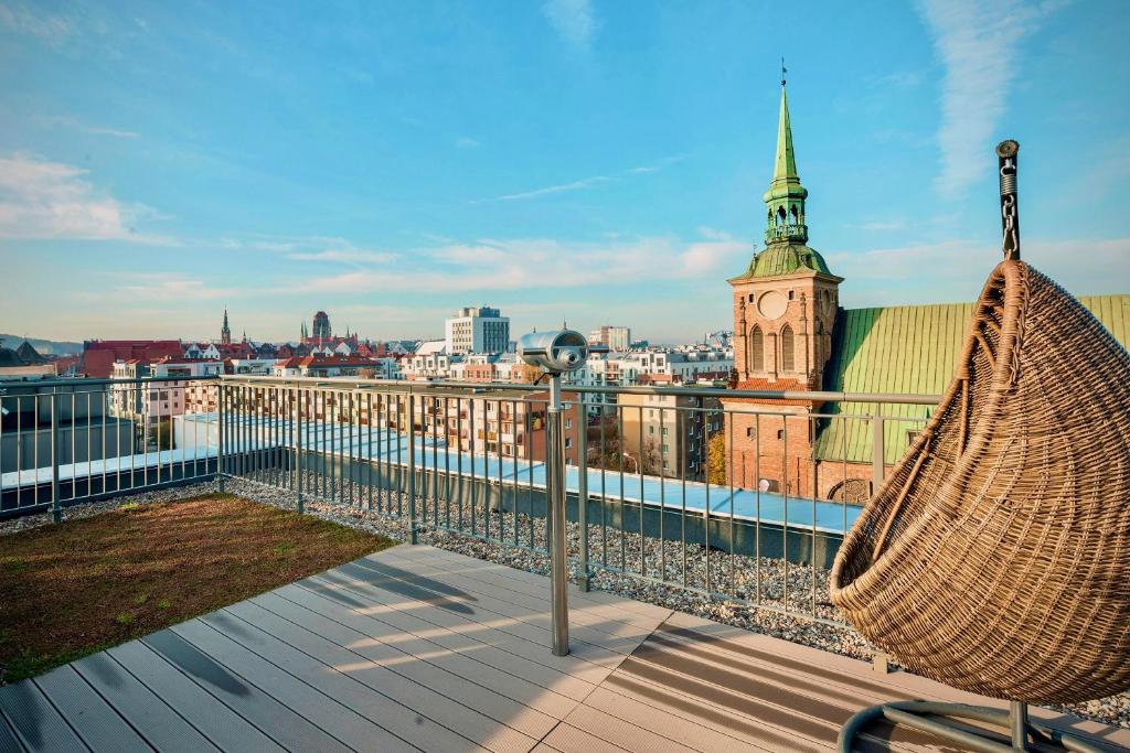 a hammock on the roof of a building with a clock tower at Blue Mandarin Garden Gates in Gdańsk