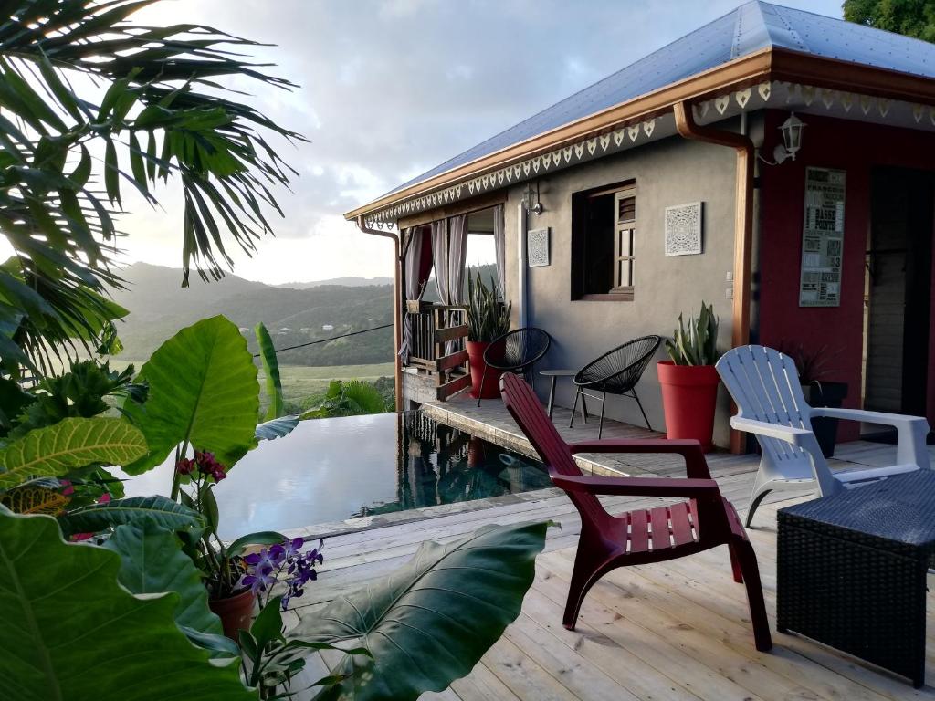 une terrasse couverte avec 2 chaises et une maison dans l'établissement Muscade lodge, au Marin
