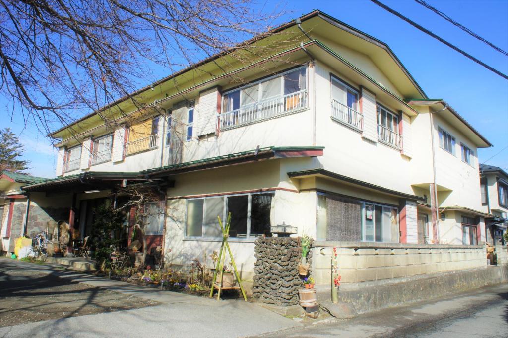 Casa blanca grande con ventanas y balcones en Ryokan Fuji Heights en Fujikawaguchiko