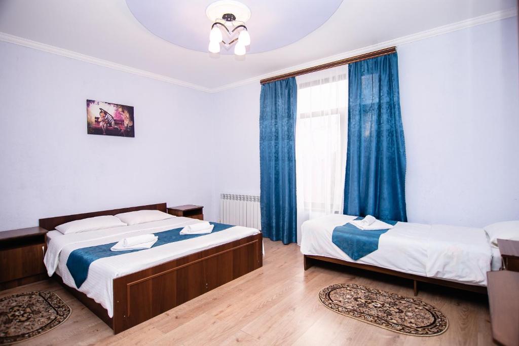 クラースナヤ・ポリャーナにあるKatrin Guest Houseの青いカーテンが備わる客室のベッド2台