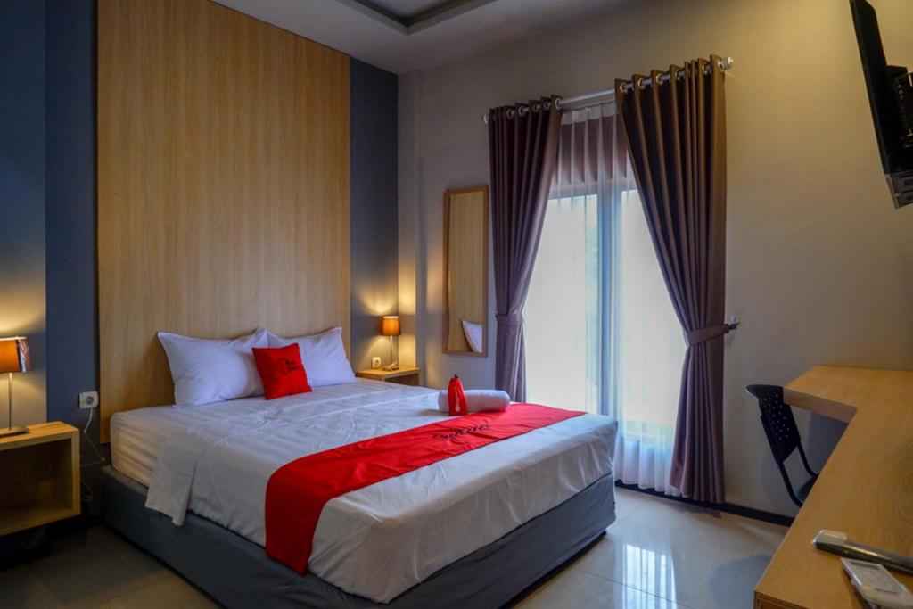 um quarto com uma cama com almofadas vermelhas e uma janela em RedDoorz Syariah @ Jalan Sultan Agung Tegal em Tegal