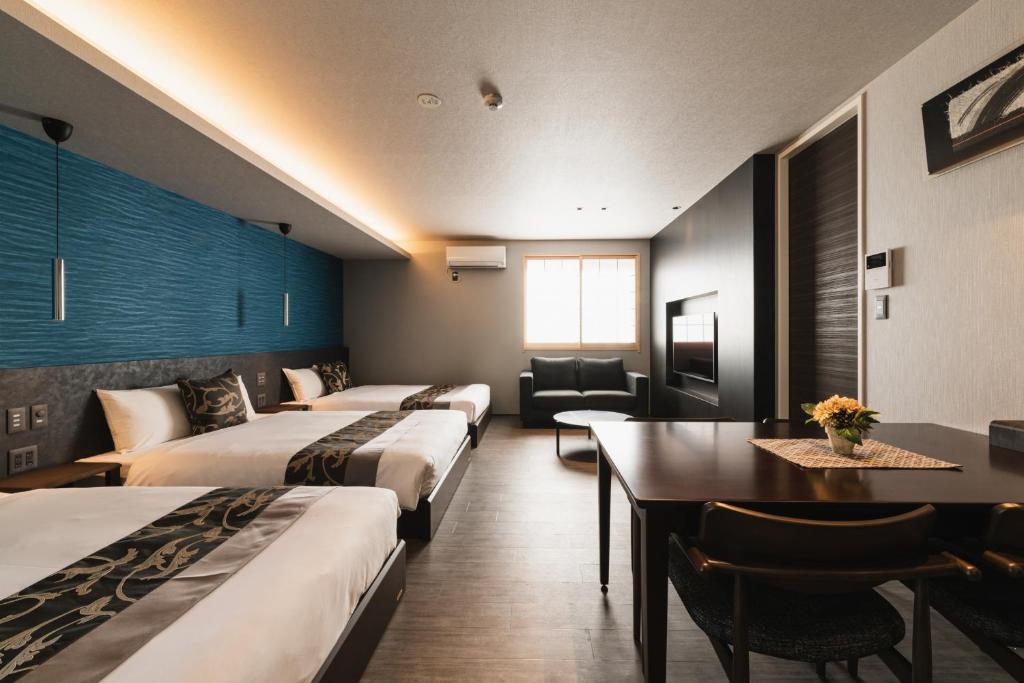 una camera d'albergo con quattro letti e un tavolo con sedie di GRAND BASE Beppu Ekihigashi a Beppu