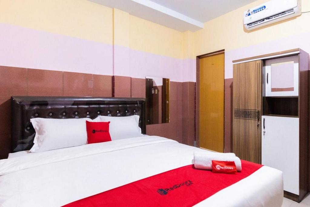 1 dormitorio con 1 cama blanca grande con almohadas rojas en RedDoorz Plus @ Jalan Gatot Subroto Medan, en Sunggal