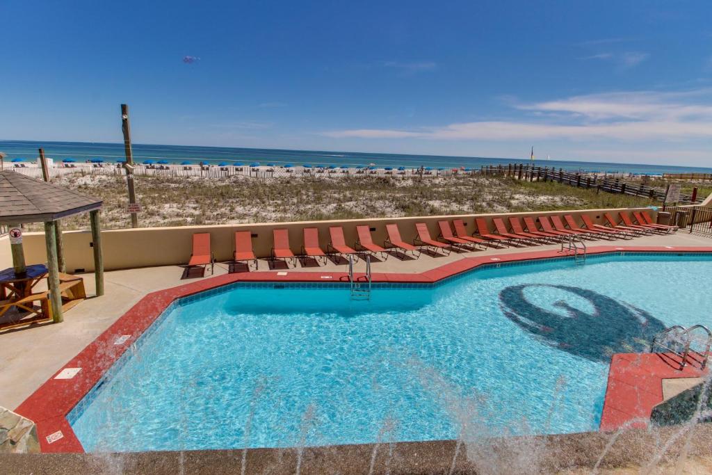 a swimming pool with chairs and the beach at Phoenix III in Orange Beach