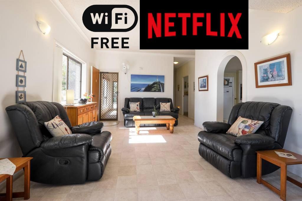 uma sala de estar com mobiliário preto e uma placa que lê netflix em Keith's Place, 1 of the 4 most popular units on Bribie em Bongaree