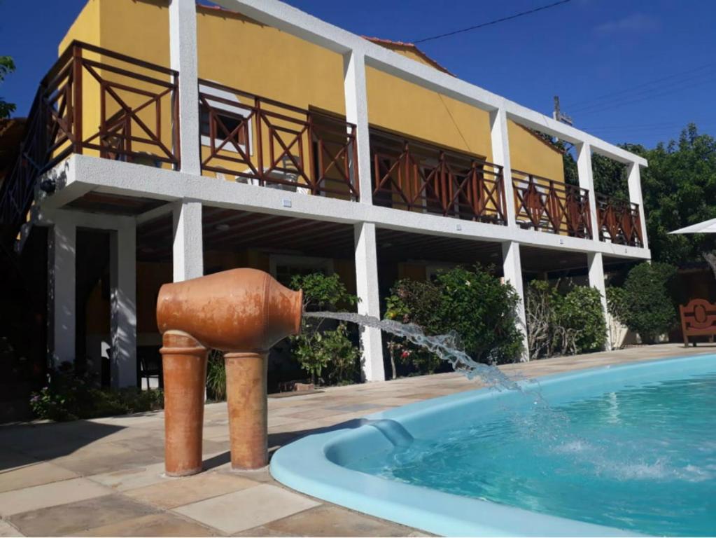 a building with a fountain in front of a swimming pool at Chalé Beija Flor in Praia do Frances