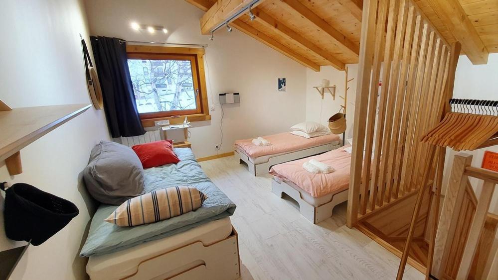 a small room with two beds and a window at Le camp de base in Chamonix-Mont-Blanc
