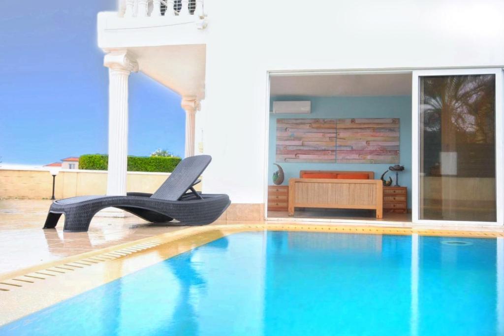 een zwembad met een stoel naast een slaapkamer bij Beach Villa Sea View, XXL Pool, 4 Bedroom in Ayia Napa