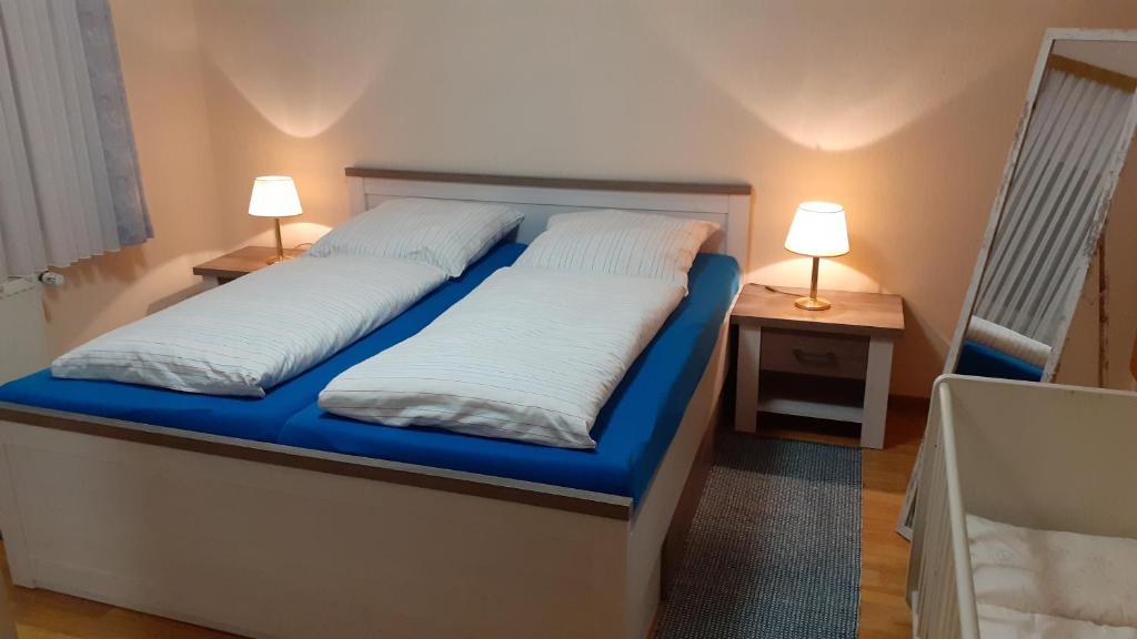 a bed in a room with two lamps on tables at Preisbewusste Ferienwohnung für 2 Personen u. Kleinkind in Utarp