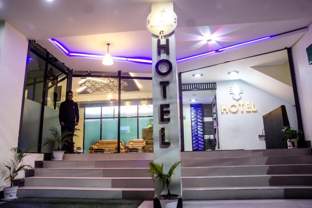 un hombre parado frente a un hotel con luces púrpuras en Royal Palm Hotel, en Sylhet