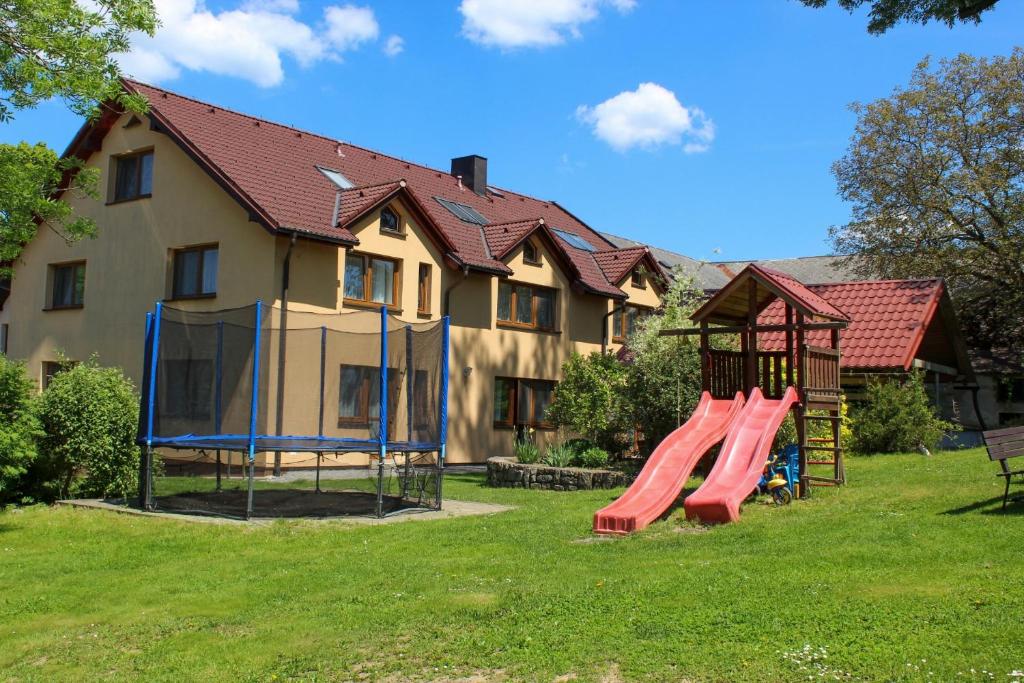 un parque infantil frente a una casa con tobogán en Penzion Na Devitce, en Světnov