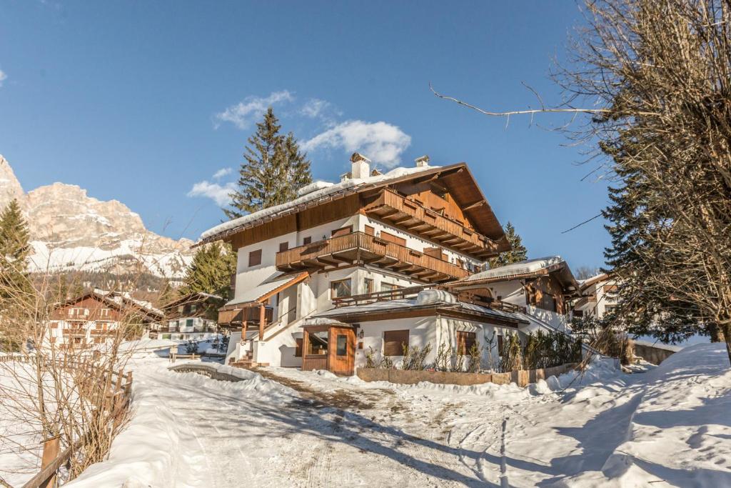 une maison dans la neige avec des montagnes en arrière-plan dans l'établissement Cantore, Cortina by Short Holidays, à Cortina dʼAmpezzo
