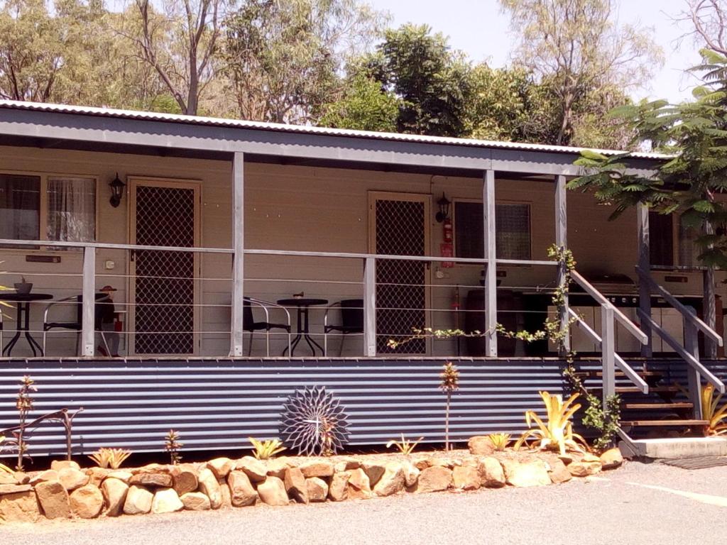 a house with a porch with tables and chairs at Silver Wattle Cabins in Mount Morgan