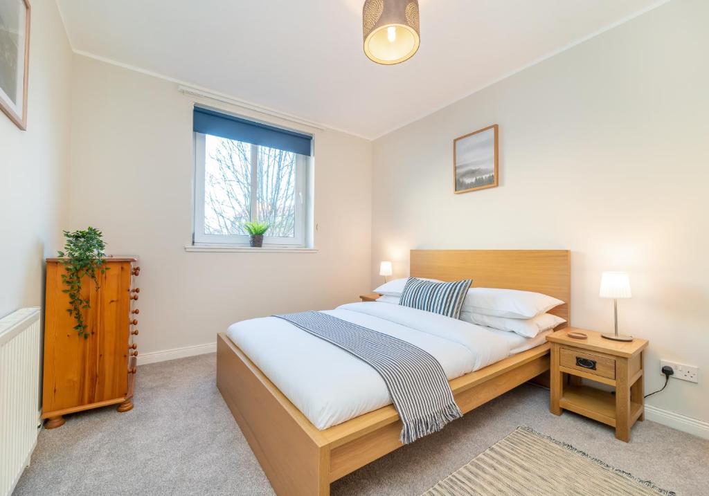 um quarto com uma cama grande e uma janela em The Waverley Park Terrace Residence em Edimburgo