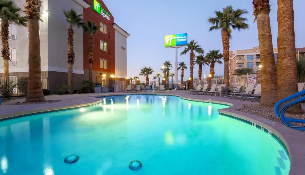 a swimming pool in front of a hotel with palm trees at Holiday Inn Express Las Vegas Stadium Area, an IHG Hotel in Las Vegas