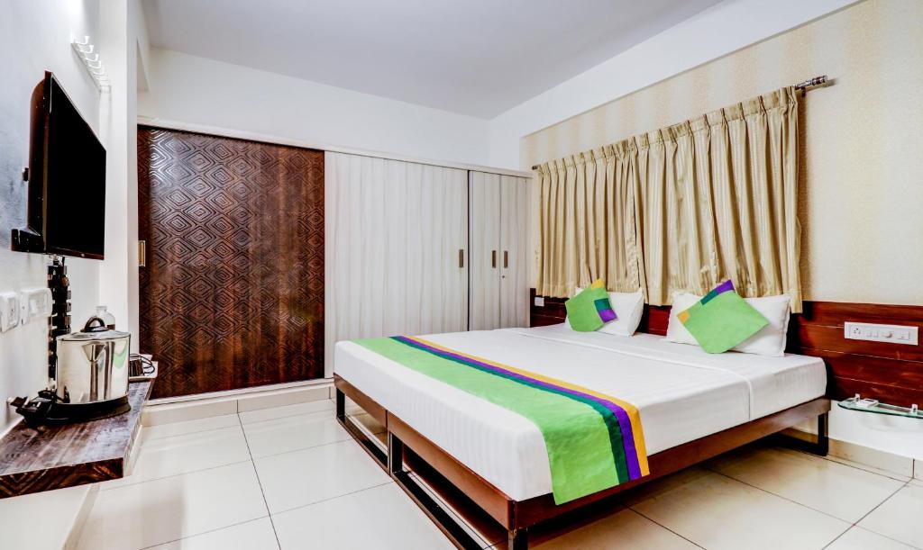 a bedroom with a large bed and a television at Treebo Trend Saga Apartment in Bangalore