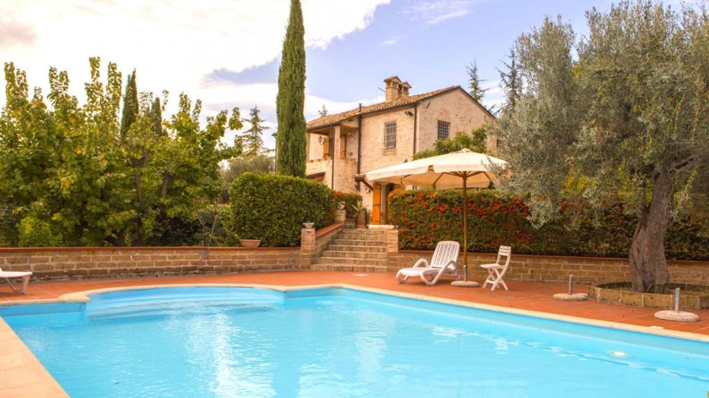 a swimming pool with two chairs and a house at Villa Anna - Homelike Villas in Montone