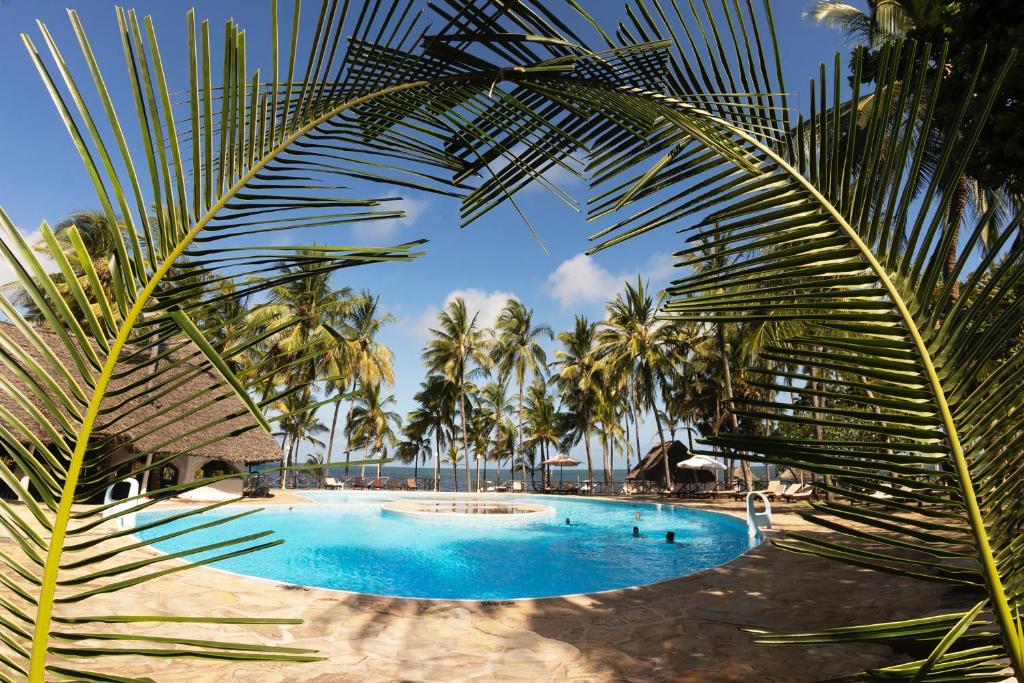 a large swimming pool with palm trees in the background at Sandies Tropical Village in Malindi