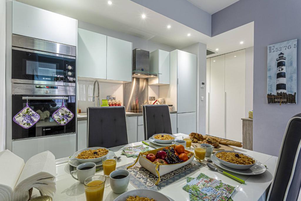 een witte keuken met een tafel met eten erop bij MY CASA - DANTE 10 in Nice