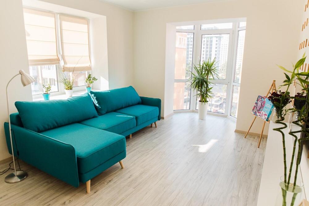 un divano blu in un soggiorno con finestre di Skandi apartment near the Park a Irpin'