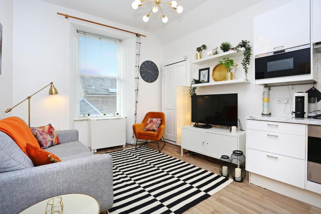 uma sala de estar com um sofá e uma televisão em JOIVY Bright 2 bed flat, sleeps 6, next to Holyrood Park em Edinburgo