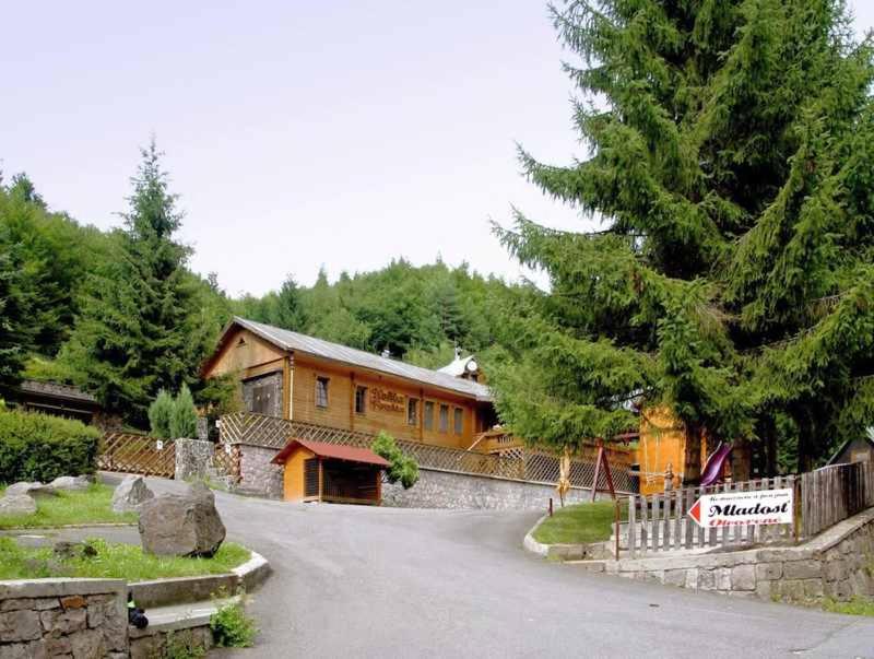 a house on a road in front of a tree at Penzión MLADOSŤ Remata in Ráztočno