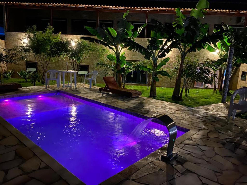 una piscina con luces púrpuras en un patio trasero por la noche en Recanto Praiana de Búzios, en Búzios