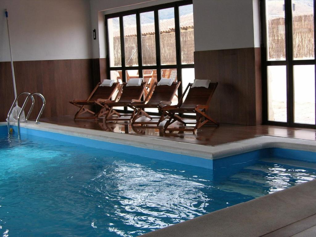 a swimming pool with two chairs and a swimming pool at casa las serijuelas in Villanueva de Ávila