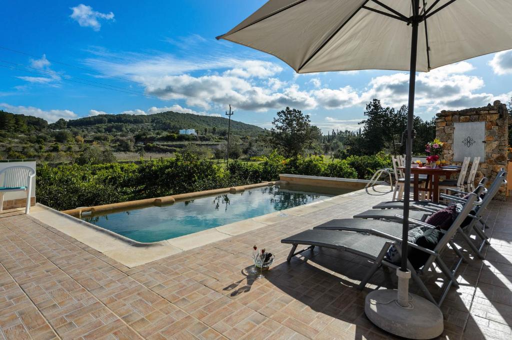 a swimming pool with a table and an umbrella at Villa Davyvic in Sant Joan de Labritja