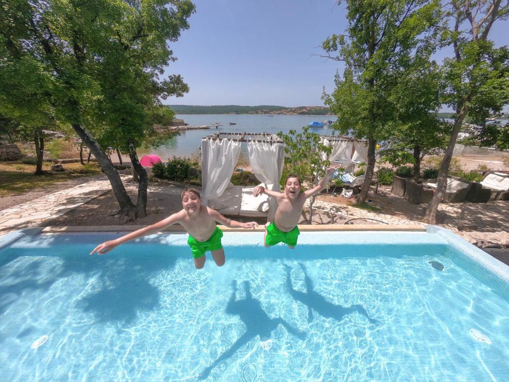 two young men jumping into a swimming pool at Krk Mobile Homes in Klimno