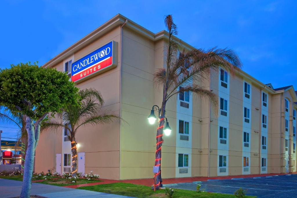 un bâtiment d'hôtel avec un panneau d'hôtel et des palmiers dans l'établissement Candlewood Suites LAX Hawthorne, an IHG Hotel, à Hawthorne