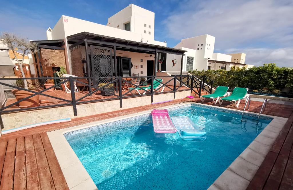 a swimming pool with chairs and a house at Paradise Villa in Corralejo